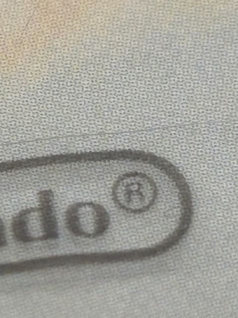 Nintendo registered trademark strip detail on authentic vs. fake DS packaging